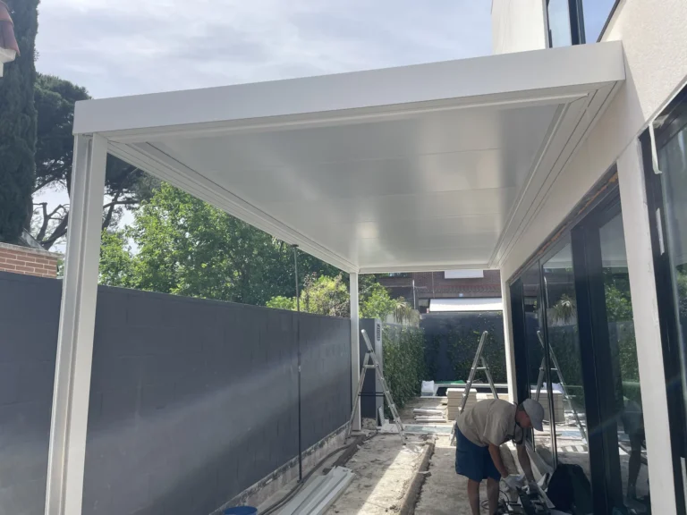 Estructura blanca de pérgola de aluminio junto a una vivienda durante el montaje