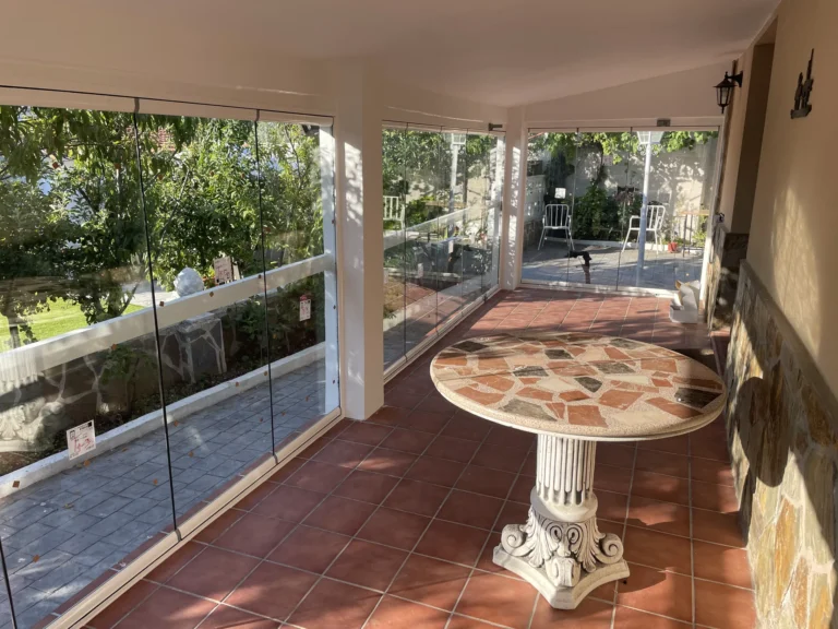 Interior de un porche con paneles de cristal hacia el jardín