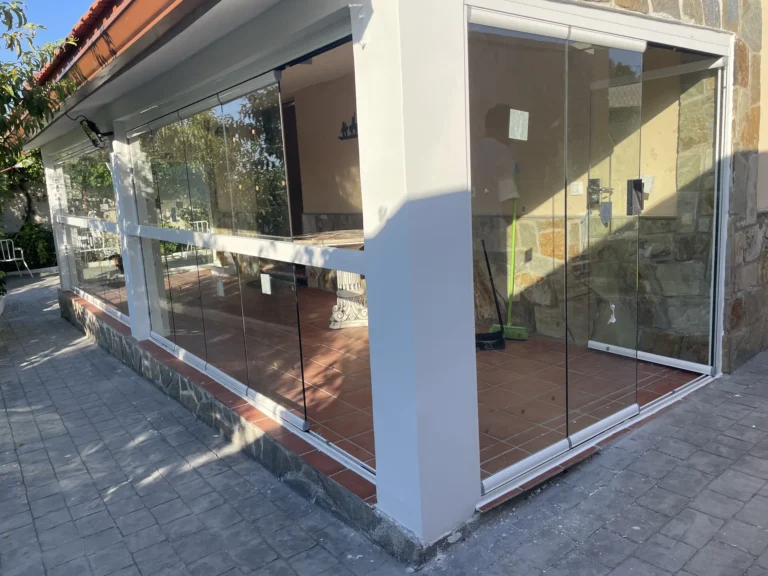Esquina exterior de un porche acristalado con paneles de cristal