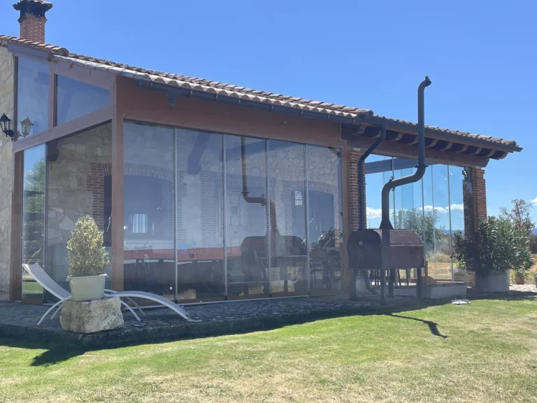 Lateral de un porche de piedra cerrado con paneles de cristal